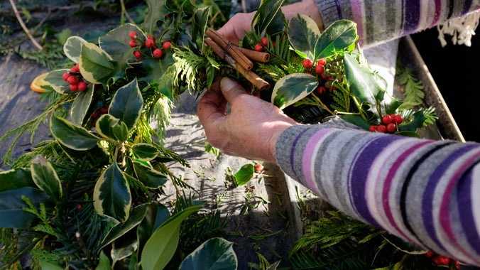 Someone making a Christmas wreath from green foliage.